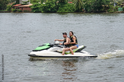 Happy young couple enjoying and having fun riding on a jet ski. Tropical coast of Sri Lanka