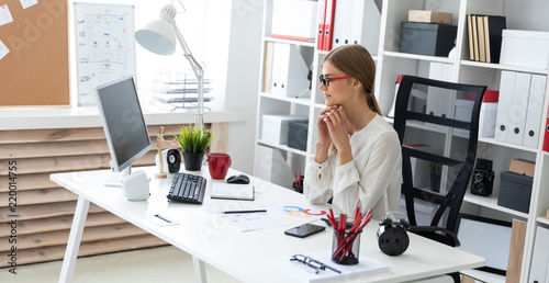 A young girl is sitting at the computer desk in the office. photo