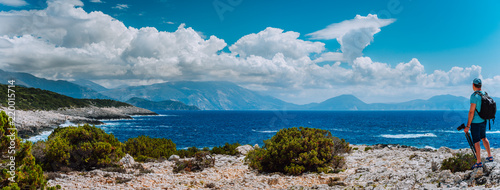 Male tourist with camera admiring breathtaking cloud scenery over the mountain range at the Mediterranean sea coast. Sunning outdoor scene of Ionian Islands, Kefalonia, Greece