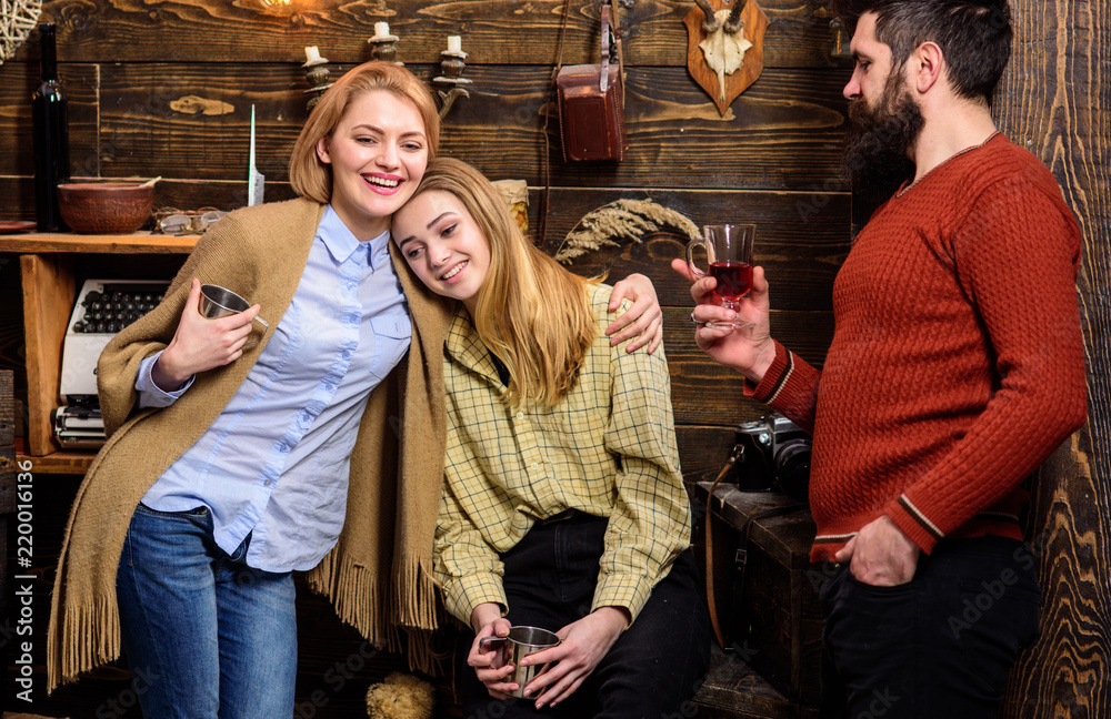 Family enjoy vacation in gamekeepers house. Friends, family spend pleasant evening, interior background. Coziness concept. Girls and man on happy faces hold metallic mugs, enjoy coziness with drinks