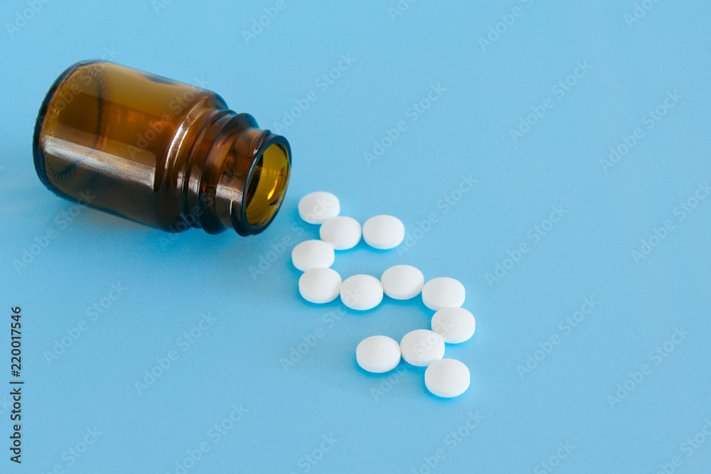 White pills spilling from a medicine bottle forming a dollar sign on a blue background. White pills spilling from a medicine bottle forming a dollar sign on a blue background.
