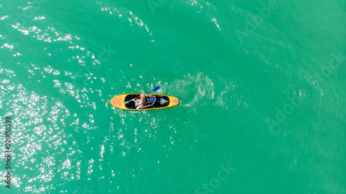 vue arienne au dessus d'un homme qui est à genou sur son paddle sur des eaux vertes