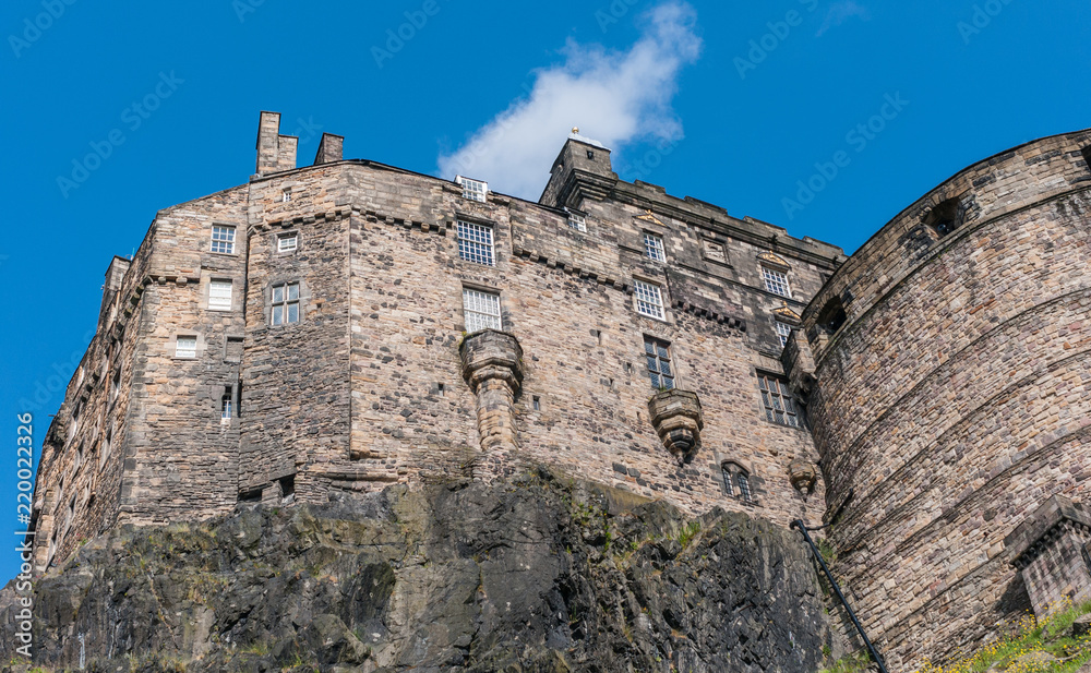 Edinburgh, Scotland, UK - June 14, 2012: Brown stone Palace block and circular half moon battery, built on volcanic rock, under blue sky with white patch of Castle.