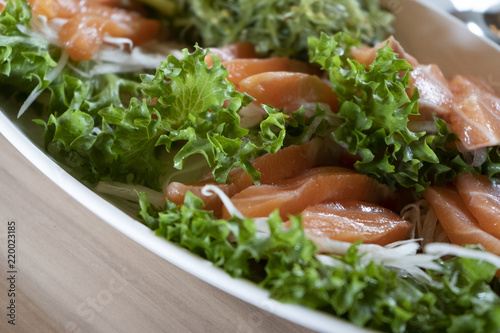 Japanese food, salmon sashimi with Seaweed and vegetables in Ceramic plate on wooden table.