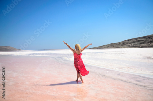 The woman in red dress walking on pink lake in Crimea © Ekaterina