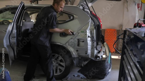 Repair man sanding on dented car.