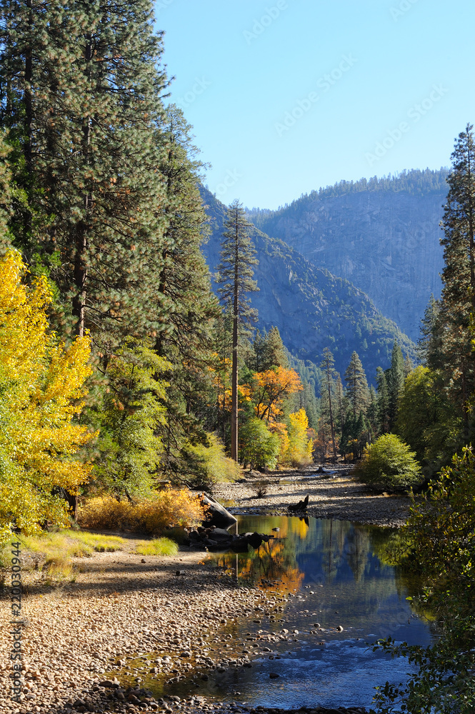 Fall foliage adorns the banks of the Merced River, cutting through Yosemite Valley National Park.