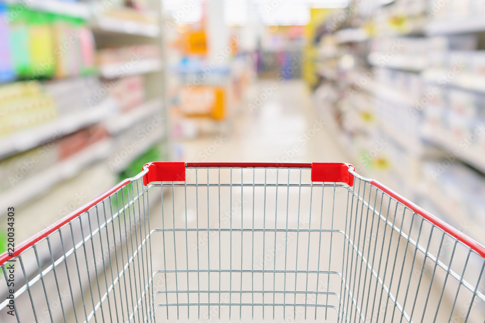 Empty shopping cart with abstract blur supermarket discount store aisle and product shelves interior defocused background Empty shopping cart with abstract blur supermarket discount store aisle and product shelves interior defocused background