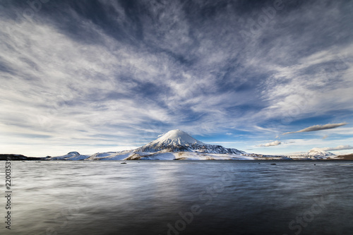 Parinacota Volcano above the horizon over Chungara lake waters an awesome and dramatic cloudy landscape inside Lauca National Park. A panoramic view of the chilean 