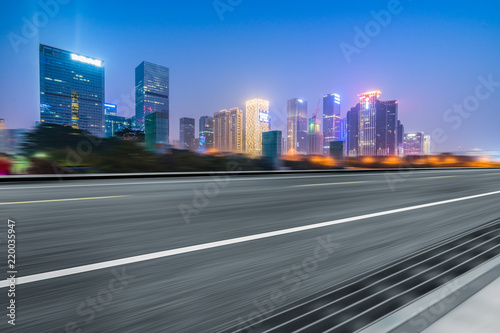 blurred asphalt road with city skyline background at night
