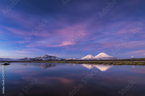 The great "Nevados de Payachatas" with the Pomerape and Parinacota Volcanoes, left and right respectively reflected over Cotacotani lagoon waters during twilight, Arica, Chile