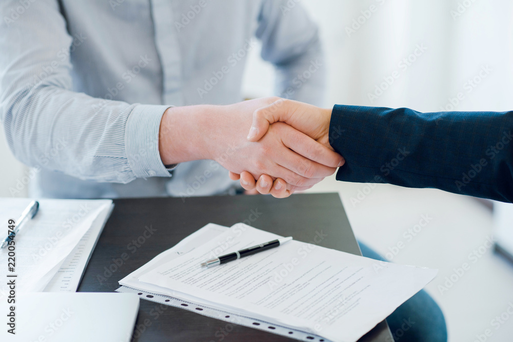 Two business man shaking hands during a meeting in the office. Documents on the table. Success deal. Dealing, greeting and partner concept. Close up Two business man shaking hands during a meeting in the office. Documents on the table. Success deal. Dealing, greeting and partner concept. Close up