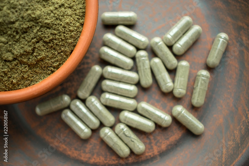 Obraz na płótnie Supplement kratom green capsules and powder on brown plate