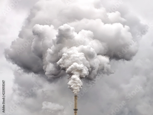 Smoke from factory pipe against dark overcast sky photo