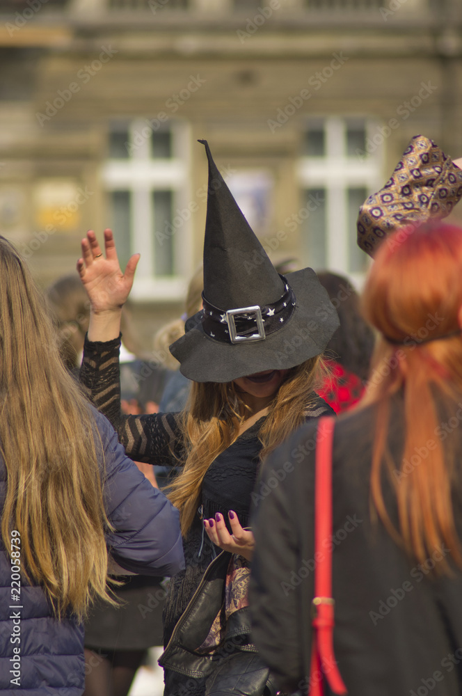 Fototapeta premium wróżka w kapeluszu gestem ręki zaczarowuje dwie kobiety