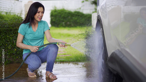 woman water spray her car wheel with water tube washing it
