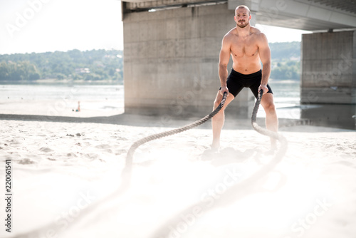 Strong man exercising with battle ropes