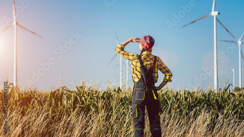 Farmer woman has invested not only in land but also wind energy watching the turbines