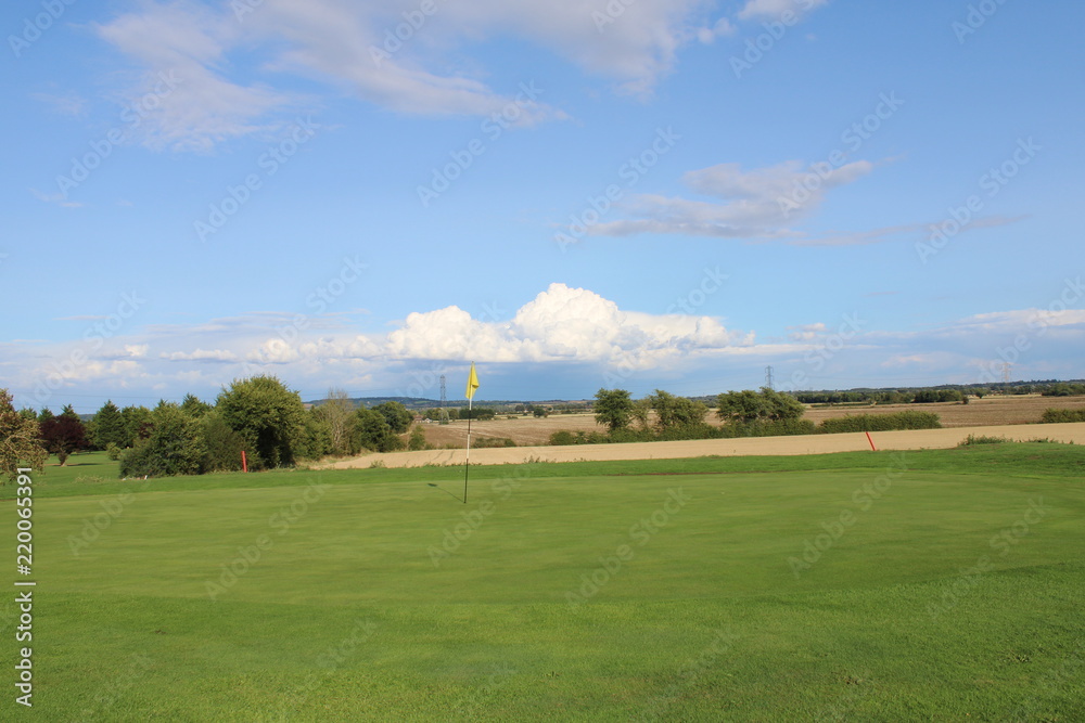 Fototapeta premium Golf green overlooking farmers field