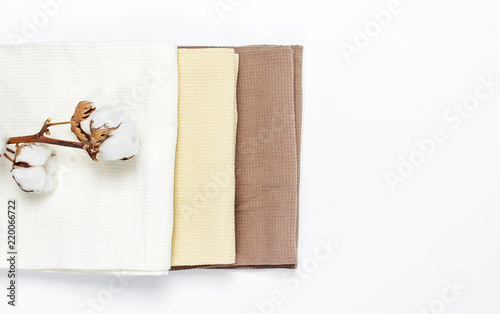 Multicolored clean towels with a branch of cotton on a white background top view with copy space. Texture of cotton, waffle towel, textiles. Towels for kitchen or Spa concept. photo