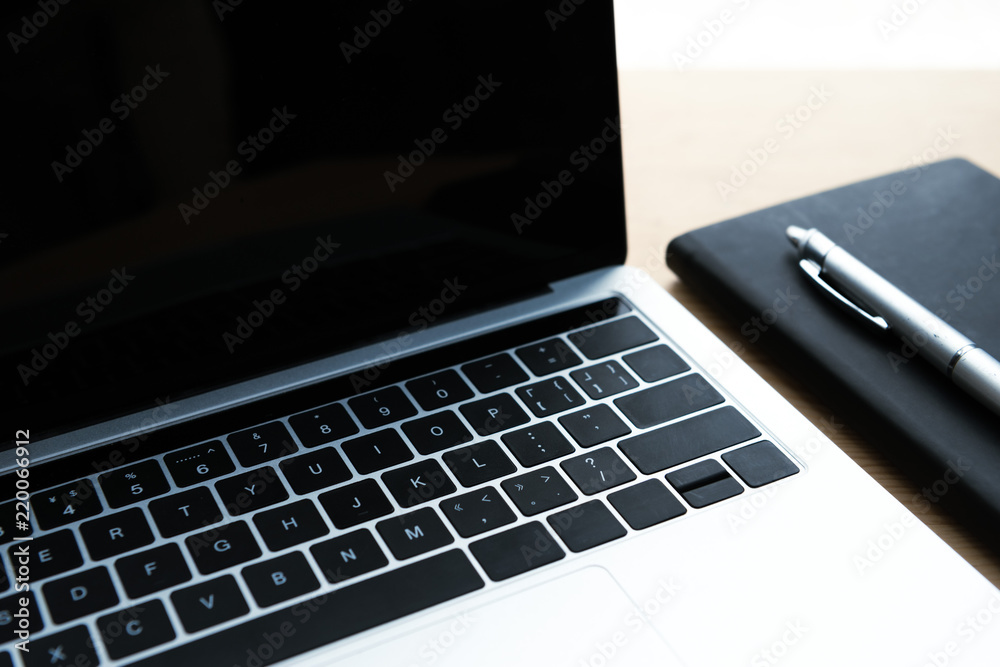 close-up view of laptop with blank screen, notebook and pen on table close-up view of laptop with blank screen, notebook and pen on table