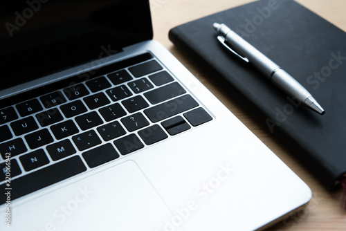 close-up view of laptop, notebook and pen on wooden table