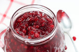 glass jar of cranberry jam on a white table, top view