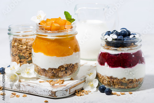 desserts with muesli, berry and fruit puree in jars on white table
