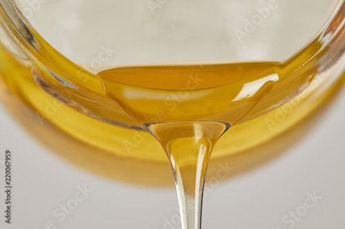 close up view of sweet honey flowing from glass jar