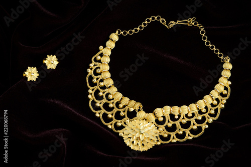 Modern golden necklace on a dark pattern