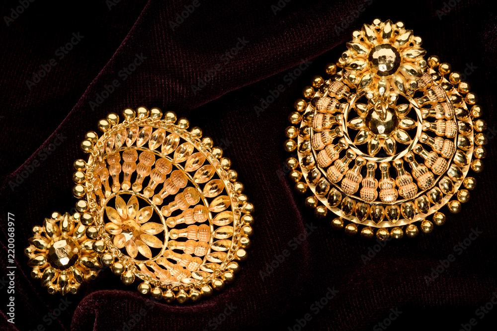 Golden earrings on a dark pattern Golden earrings on a dark pattern