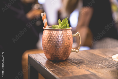 Fototapeta Close up on a copper cup with Moscow Mule cocktail, fresh mint as decoration and