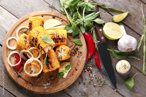 Composition with delicious grilled corn on wooden table