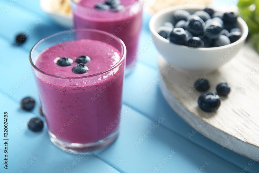 Glass with tasty blueberry smoothie on color wooden table Glass with tasty blueberry smoothie on color wooden table
