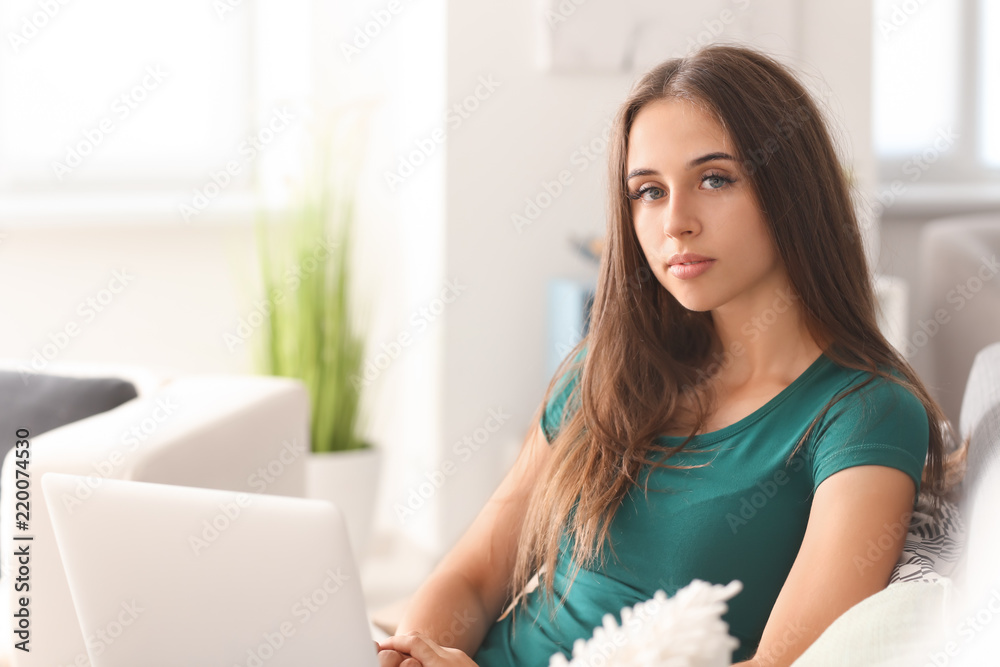 Beautiful young woman with laptop sitting on sofa at home Beautiful young woman with laptop sitting on sofa at home