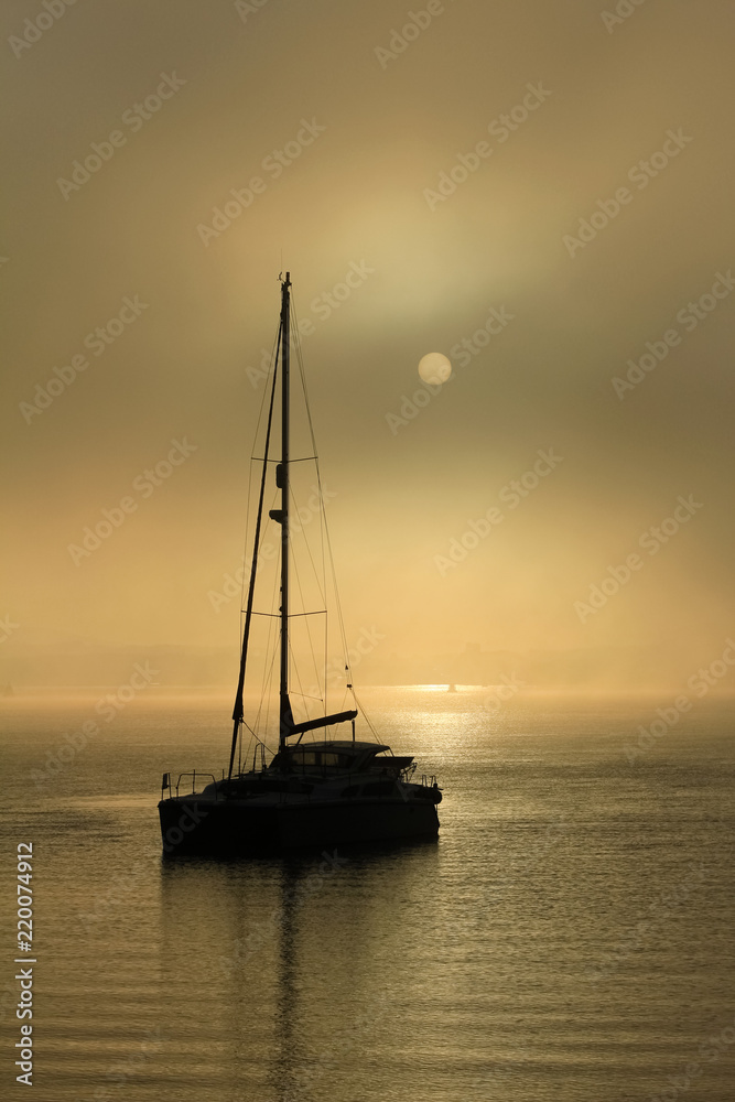 Yacht at anchor on misty morning