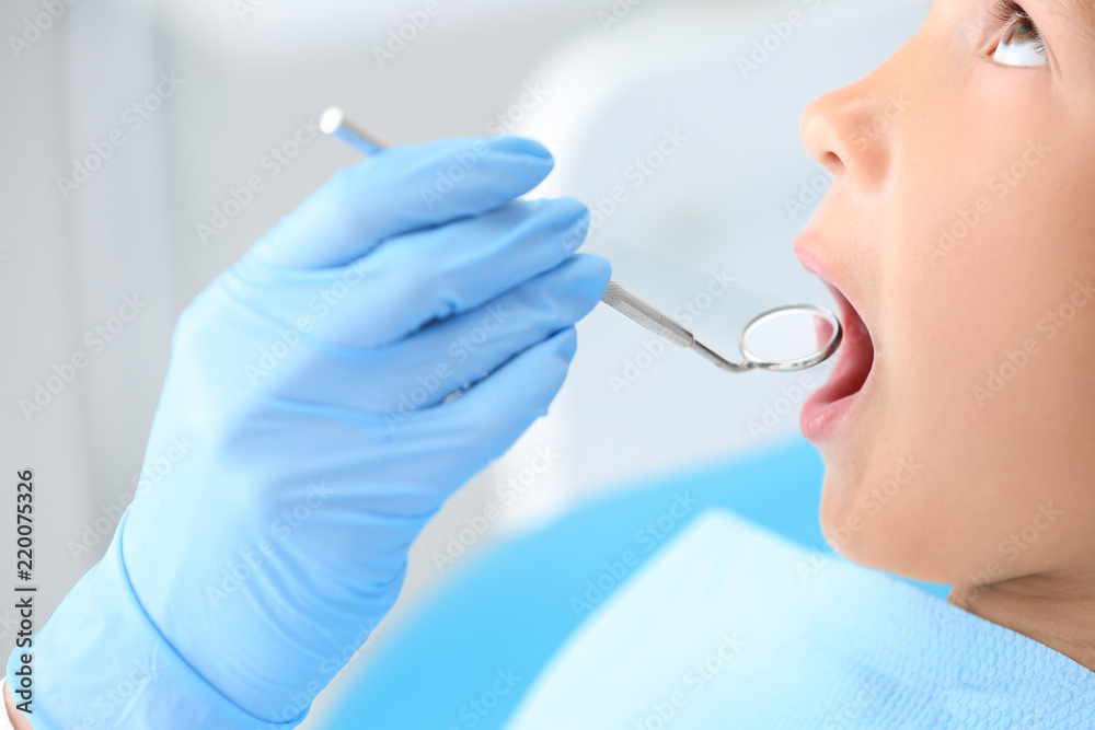 Dentist examining little boy's teeth in clinic, closeup Dentist examining little boy's teeth in clinic, closeup