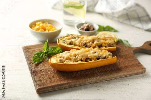 Board with quinoa stuffed zucchini boats on white wooden table