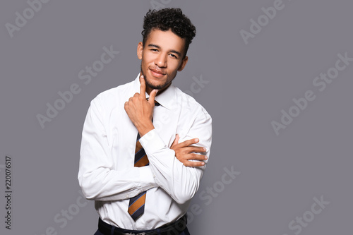 Handsome African-American businessman on grey background