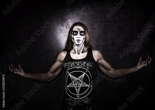 Long haired man in goth style clothes with Satan symbols. photo