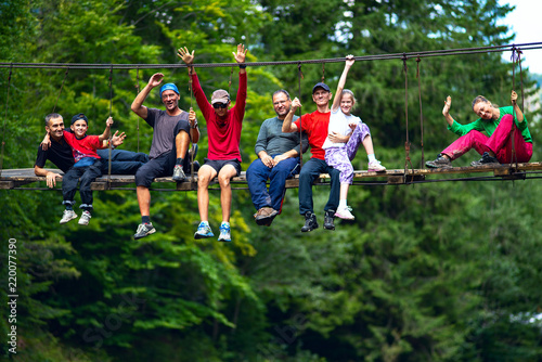 Happy travelers, friends sit on the suspension bridge