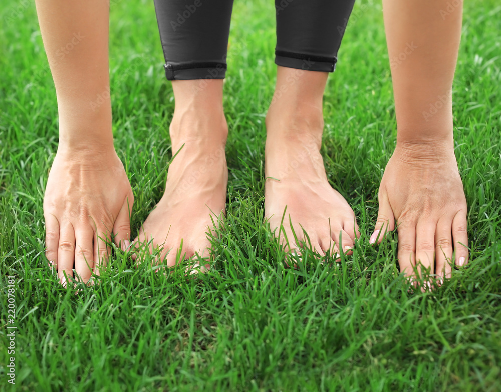 Young woman practicing yoga on green grass, closeup