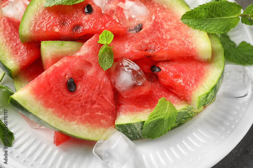 Sweet watermelon slices and ice cubes on plate, closeup