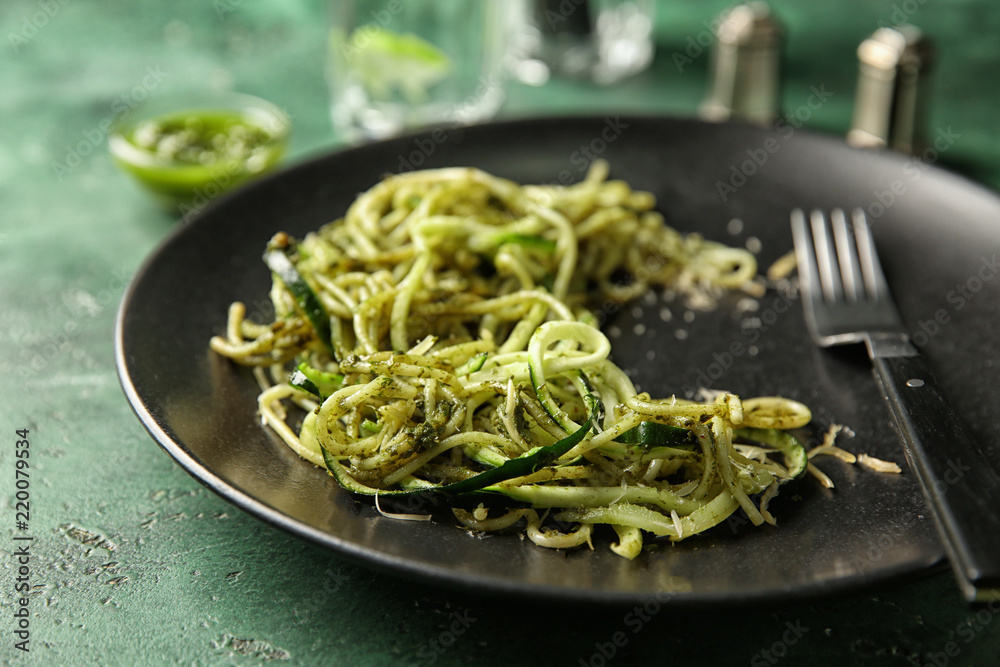 Plate of spaghetti with zucchini and pesto sauce on table, closeup