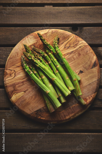 Banches of fresh green asparagus on wooden background, top view