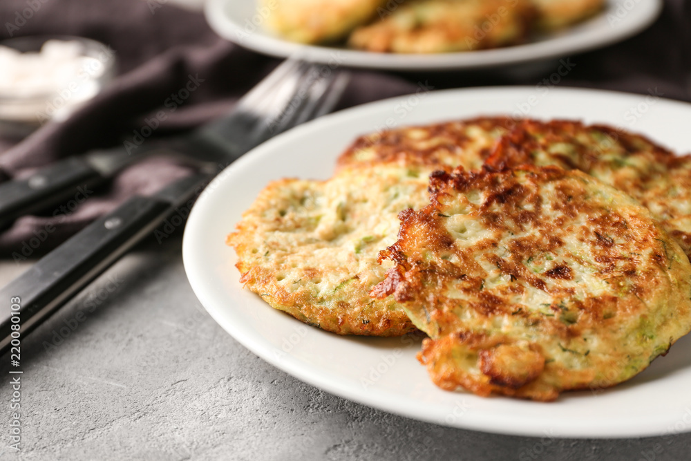 Plate with zucchini pancakes on table, closeup Plate with zucchini pancakes on table, closeup