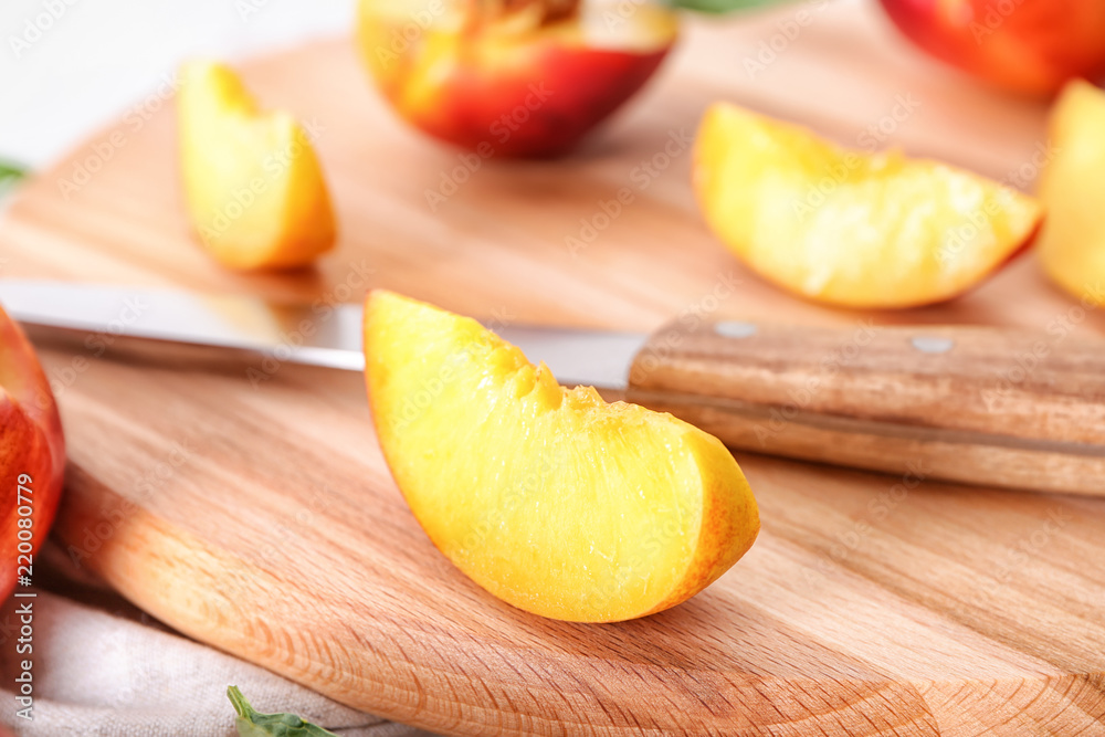 Slice of fresh peach with knife on wooden board, closeup