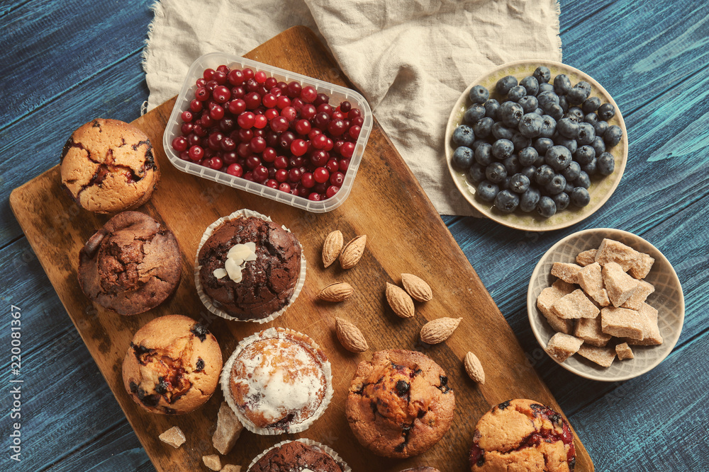 Fototapeta premium Board with tasty muffins and berries on wooden table
