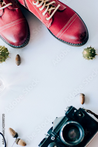 fashion leather shoes for autumn, spring. red boots on a white background lie with the camera, glasses and acorns.