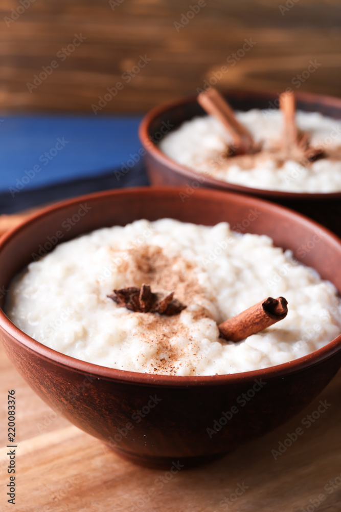 Delicious rice pudding with cinnamon and anise in bowl on wooden board, closeup Delicious rice pudding with cinnamon and anise in bowl on wooden board, closeup